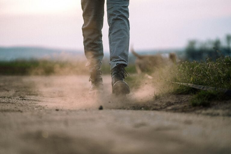 person in black and white striped pants walking on dirt road during daytime