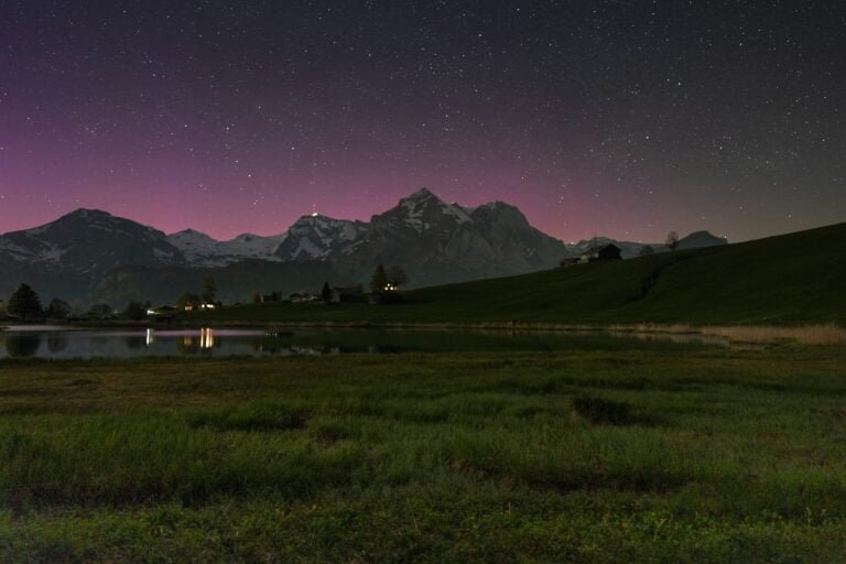 A field with a lake and mountains in the background