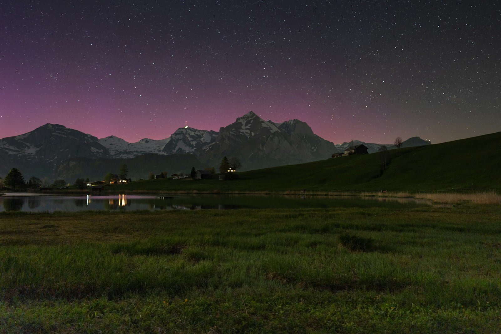 A field with a lake and mountains in the background
