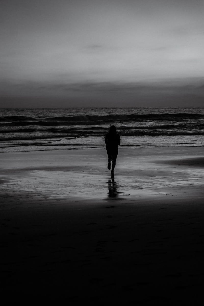 man in black jacket walking on beach during daytime